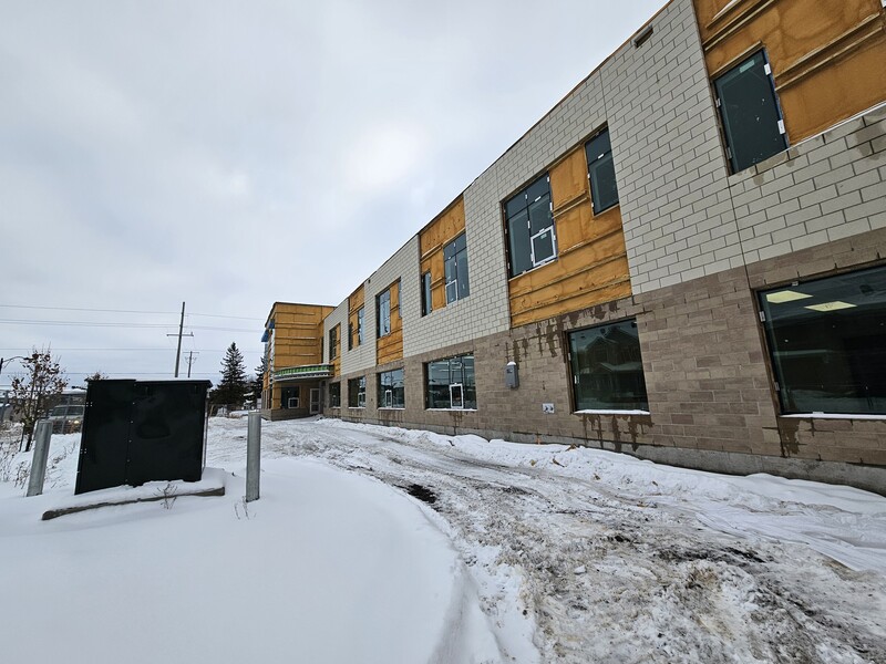 Façade en construction de la nouvelle École élémentaire catholique Avalon III, montrant le bâtiment à deux étages avec des fenêtres installées, des sections encore en cours de finition et un sol enneigé.