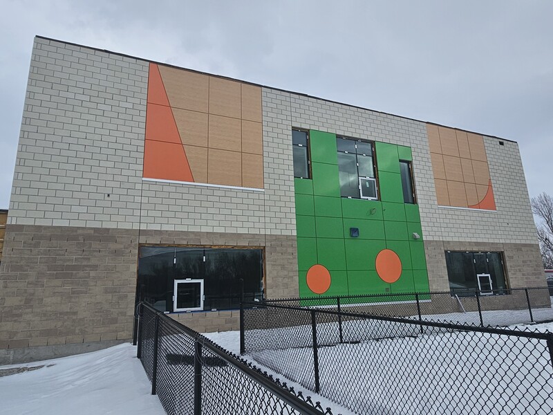 Vue extérieure de la nouvelle École élémentaire catholique Avalon III en construction, avec une façade colorée et un terrain enneigé.