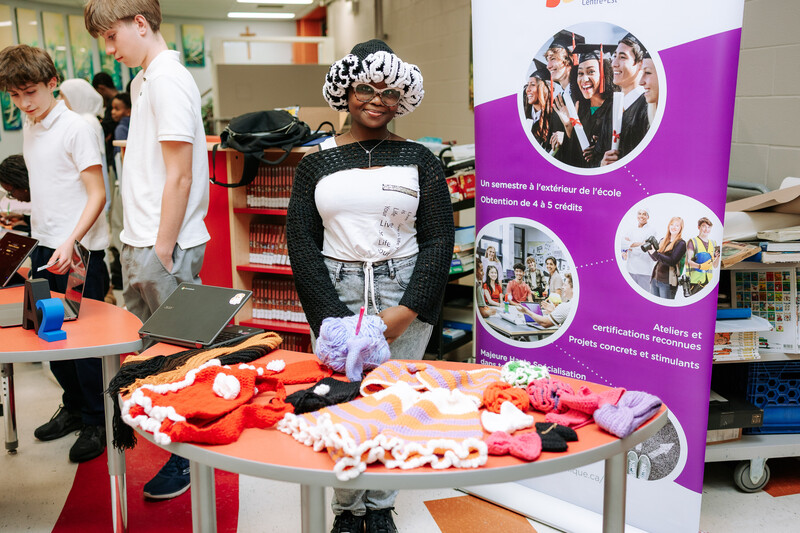 Une élève entrepreneure pose devant son stand de créations en crochet.