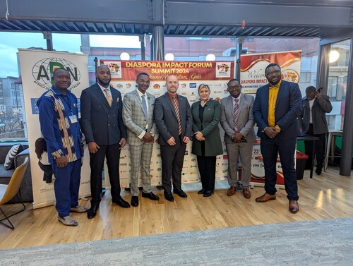 Groupe de personnes debout devant une bannière du Diaspora Impact Forum 2024 lors d’un événement officie