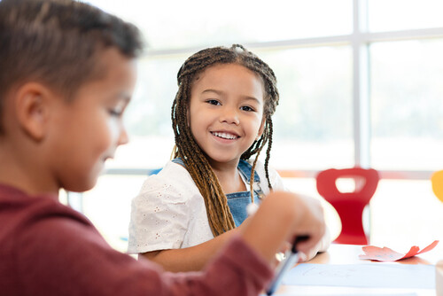 Élève souriante, assise en salle de classe