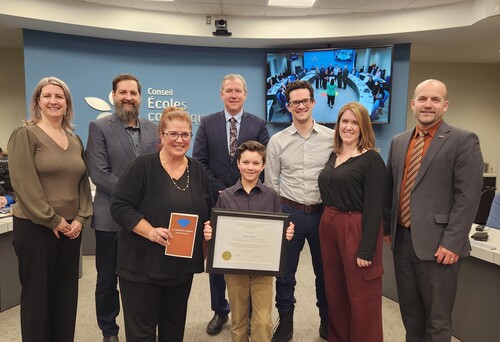 Un élève tient un certificat entouré de membres du personnel du CECCE lors d’une reconnaissance officielle.