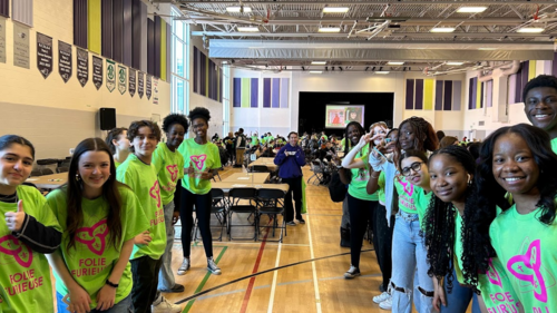 Groupe d'élèves rassemblés dans un gymnase, souriants et vêtus de vert, à l'occasion de l'événement Folie Furieuse