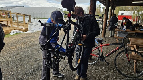 Élève réparant un vélo avec l’aide d’un expert lors d’un atelier de mécanique au Centre agro-éducatif du CECCE.