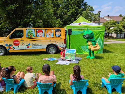 Camille La chenille, la mascotte du conseil participe à une lecture de conte dans un parc avec les enfants