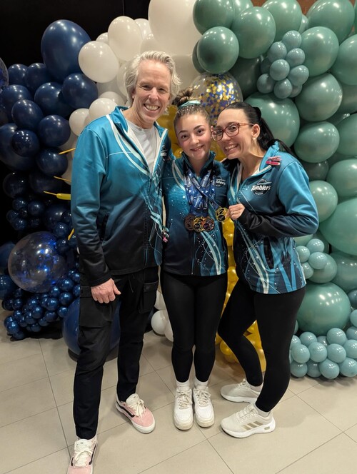 Noémie Sauvé pose avec ses entraîneurs et ses médailles lors d’une compétition de gymnastique.
