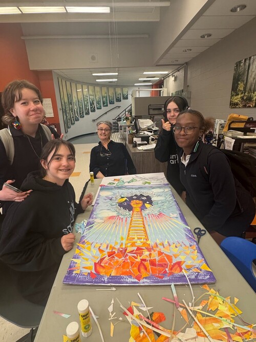 Élèves et membre du personnel réalisant une œuvre artistique collaborative en classe.