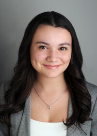  Portrait professionnel de Virginie Comeau souriante, portant un veston gris, un haut blanc et un collier argenté en forme de cœur.