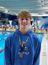 Jonathan Gallacher portant sa médaille devant une piscine de compétition.