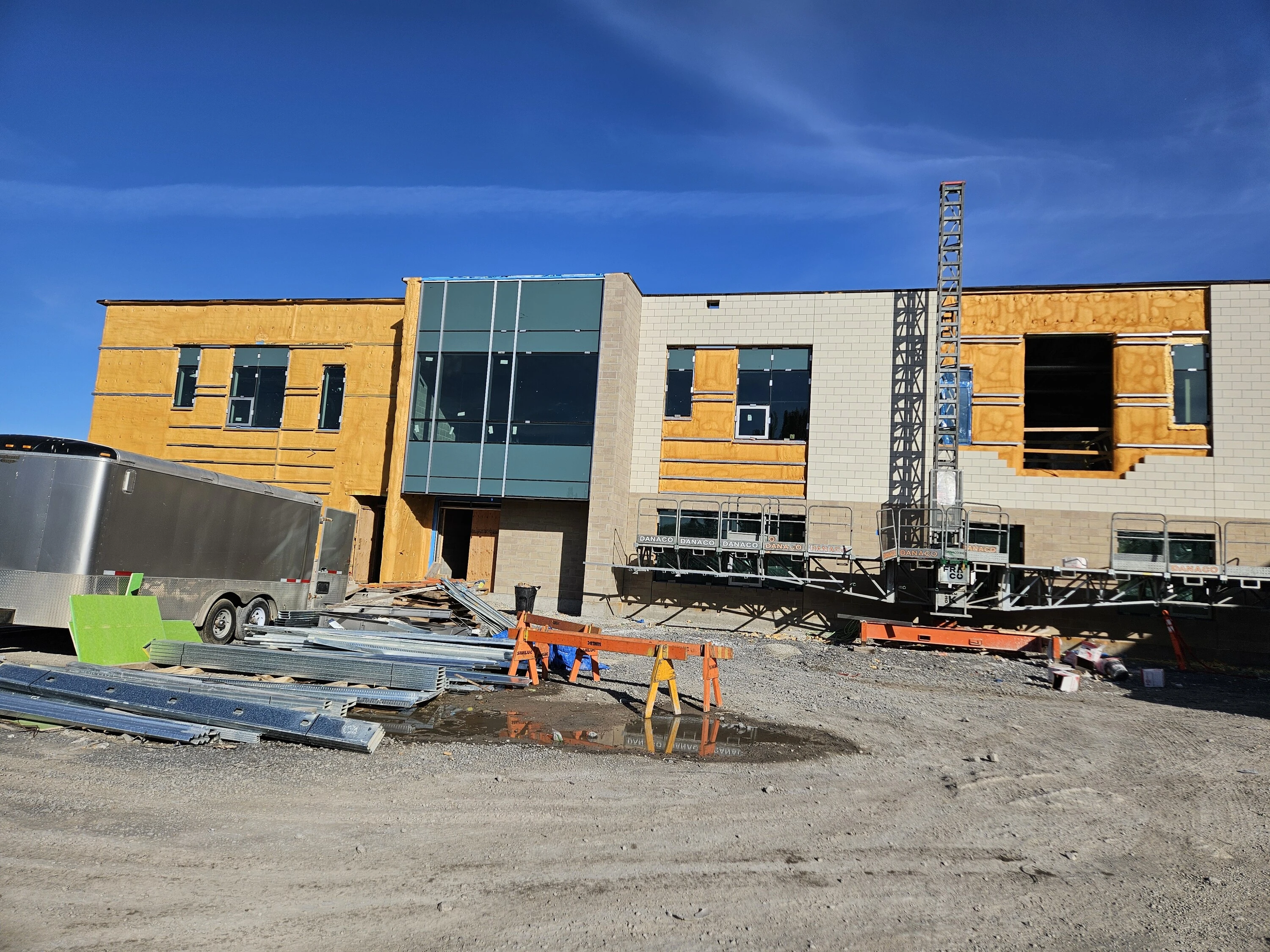 Photo du chantier de l'école en construction avec une façade partiellement terminée.