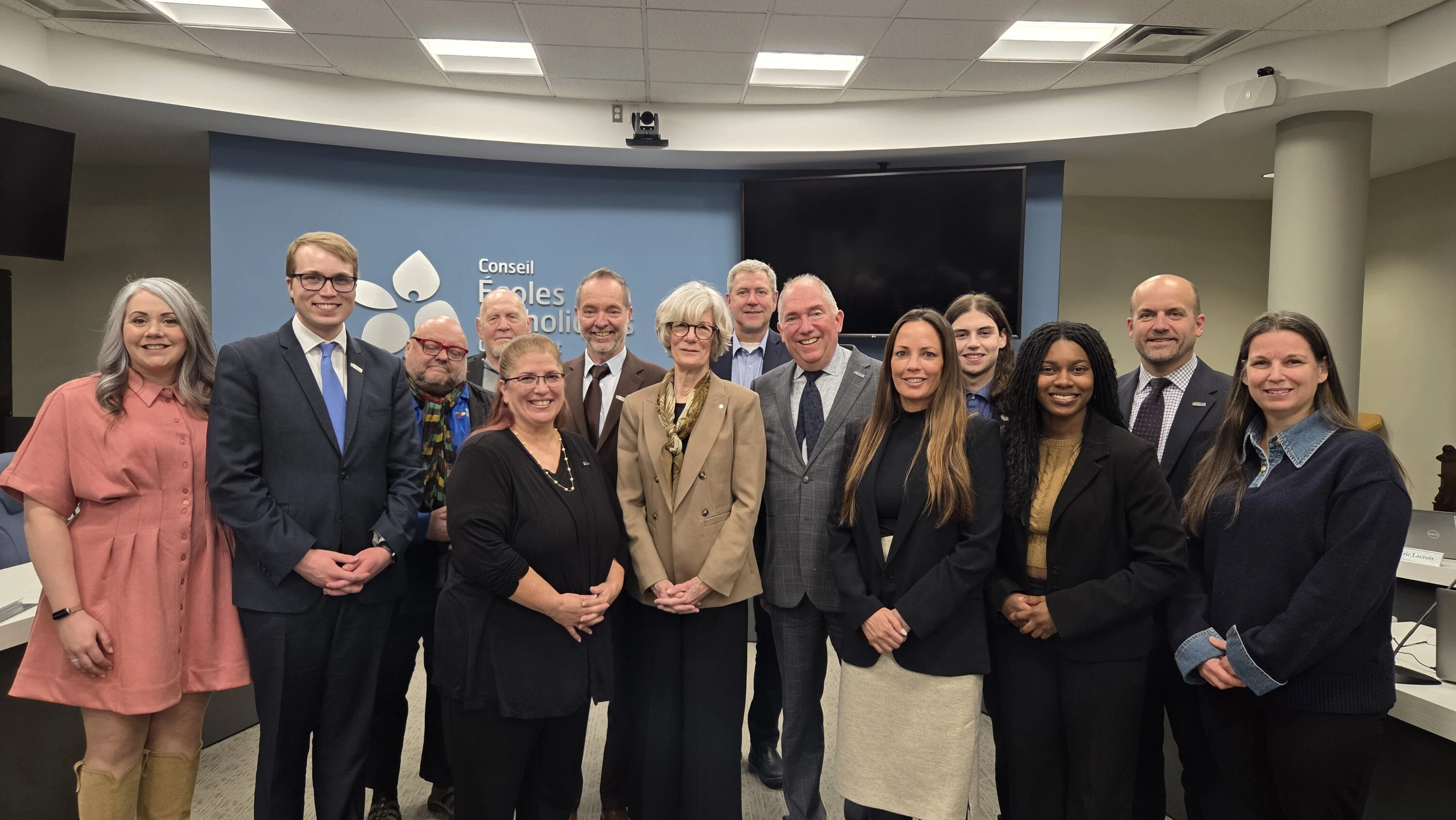 Un groupe d’adultes pose ensemble dans une salle de réunion devant un mur du CECCE.
