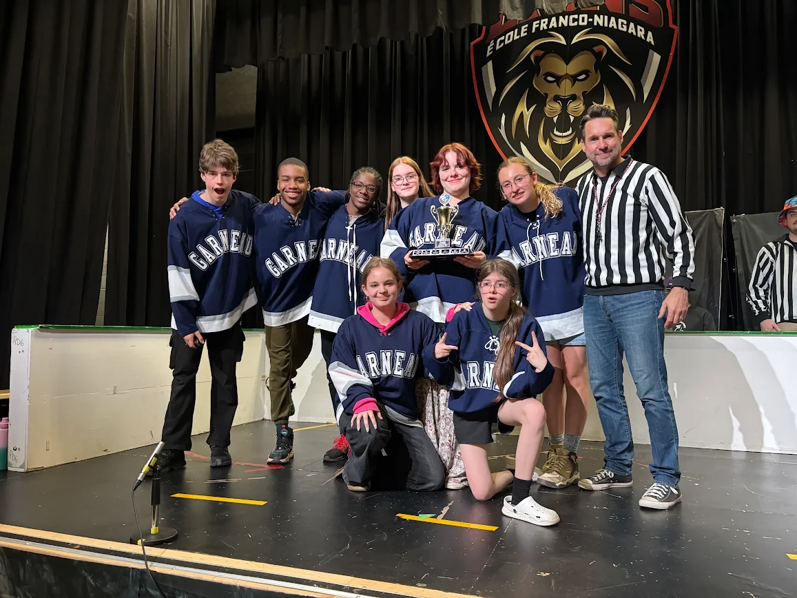 Élèves de l’École secondaire catholique Garneau posant avec leur trophée sur scène.