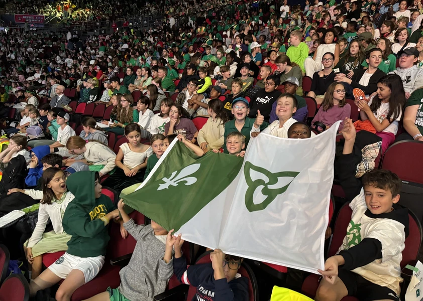Une foule d'élèves du CECCE célèbre dans les gradins de la Place TD brandissant fièrement le drapeau franco-ontarien.