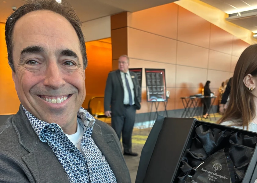Pierre Thériault tient son trophée d’Éducateur de l’année des Olympiques spéciaux Ontario – Ottawa et sourit à l’objectif.