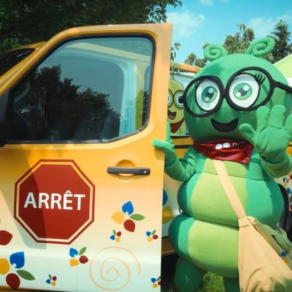 Camille La chenille, la mascotte du conseil devant son bus jaune du CECCE