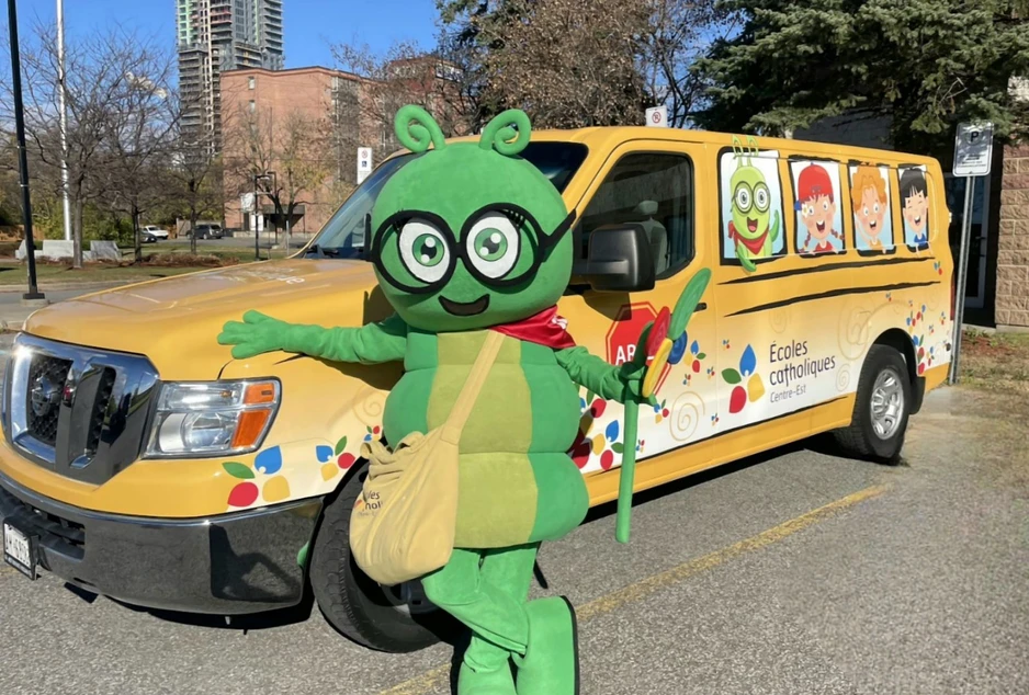 Camille La chenille, la mascotte du conseil devant son bus jaune du CECCE