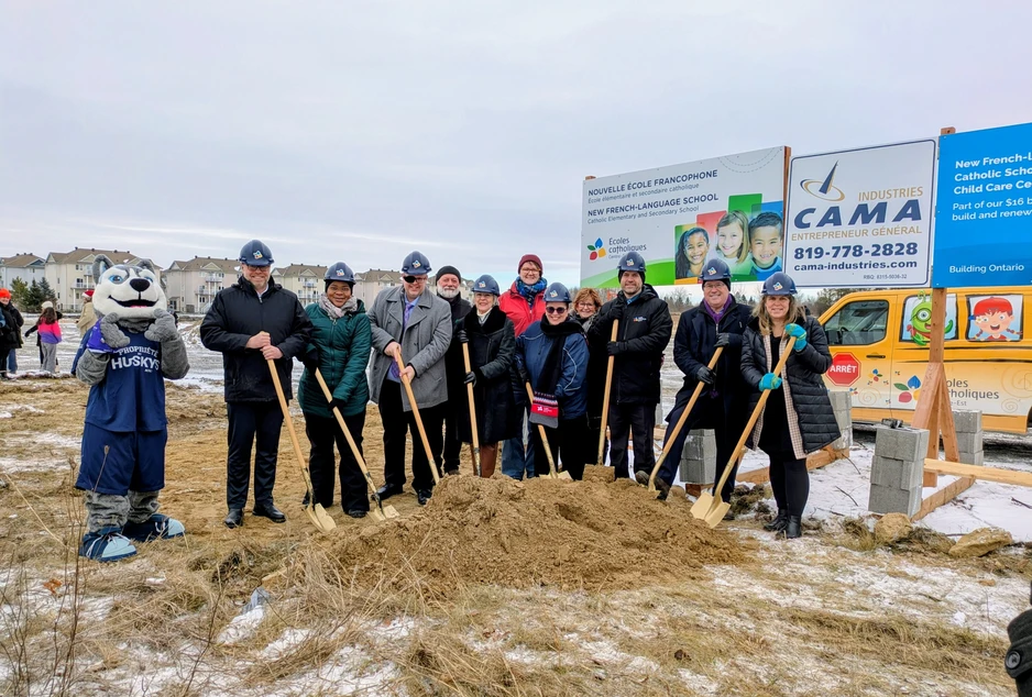 Des représentants du CECCE et des représentants politiques prennent la pose pour la pelletée de terre officielle. Ils portent un casque de construction et tiennent du pelle.
