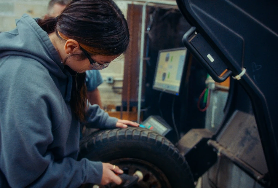 Élève en habit de sécurité qui place un pneu