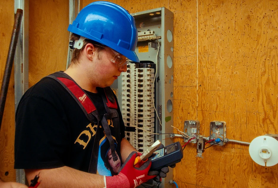 élève avec son équipement de protection devant un panneau électrique