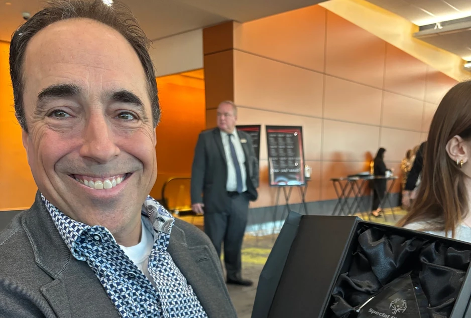 Pierre Thériault tient son trophée d’Éducateur de l’année des Olympiques spéciaux Ontario – Ottawa et sourit à l’objectif.