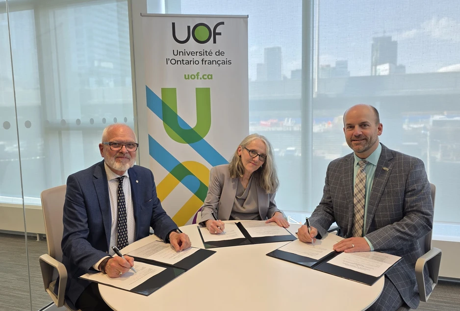 Marc Bertrand, directeur de l’éducation du CECCE, Normand Labrie, recteur et vice-chancelier de l’UOF, et Isabelle Dostaler, vice-rectrice aux études et à la recherche de l’UOF, sont assis autour d’une table et signent des documents officiels, devant une bannière de l’Université de l’Ontario français (UOF), dans un espace lumineux avec vue urbaine.