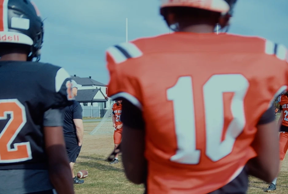 Des élèves en tenue de football dans un stade, sur le gazon du Collège catholique Mer Bleue