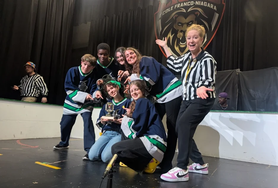 Équipe d’improvisation d’élèves posant avec leur trophée sur scène après une victoire lors d’un tournoi.