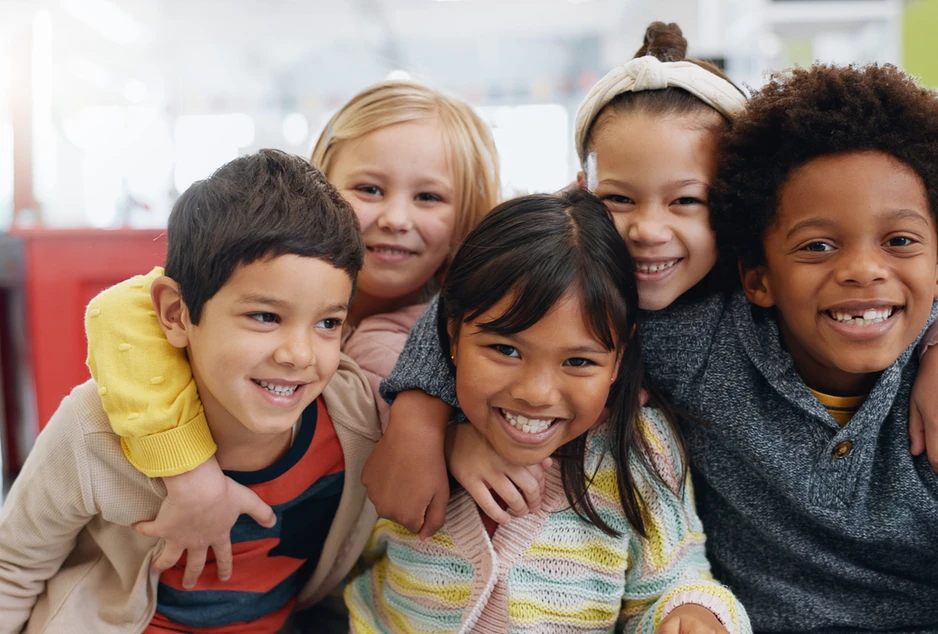Cinq enfants souriants se tiennent dans les bras les uns des autres.