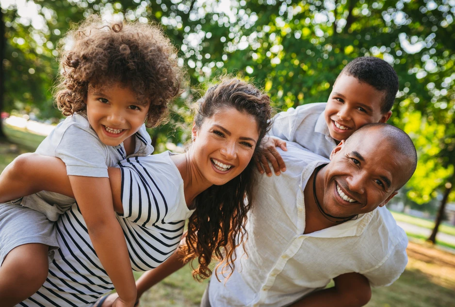 Famille souriante réunie dans un parc.