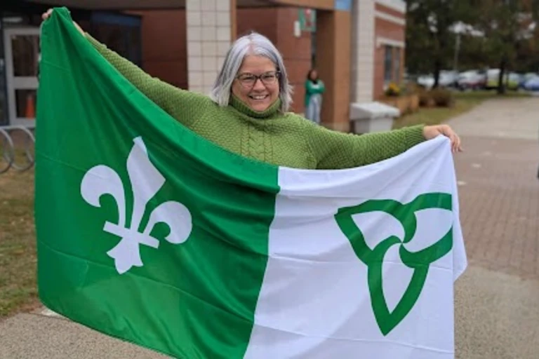 femme tenant un grand drapeau franco-ontarien