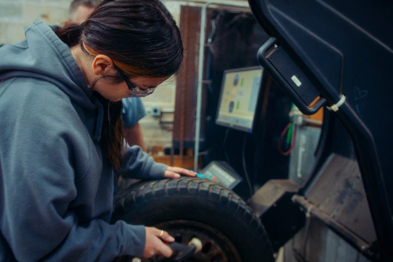 Élève en habit de sécurité qui place un pneu