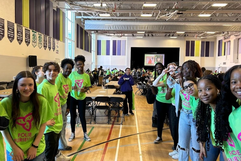 Groupe d'élèves rassemblés dans un gymnase, souriants et vêtus de vert, à l'occasion de l'événement Folie Furieuse