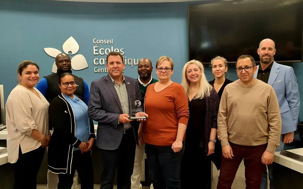 10 membres du personnel posant ensemble au Centre éducatif. Tout le groupe sourit et le directeur des ressources humaines tient en main le prix.