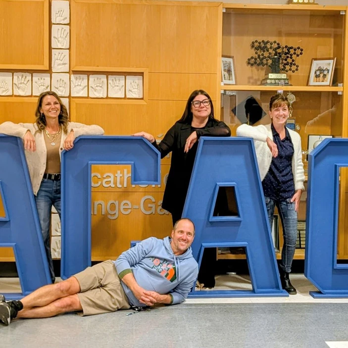 Membres du personnel posant derrière de grandes lettres bleues formant « ACAG », décorées de ballons.