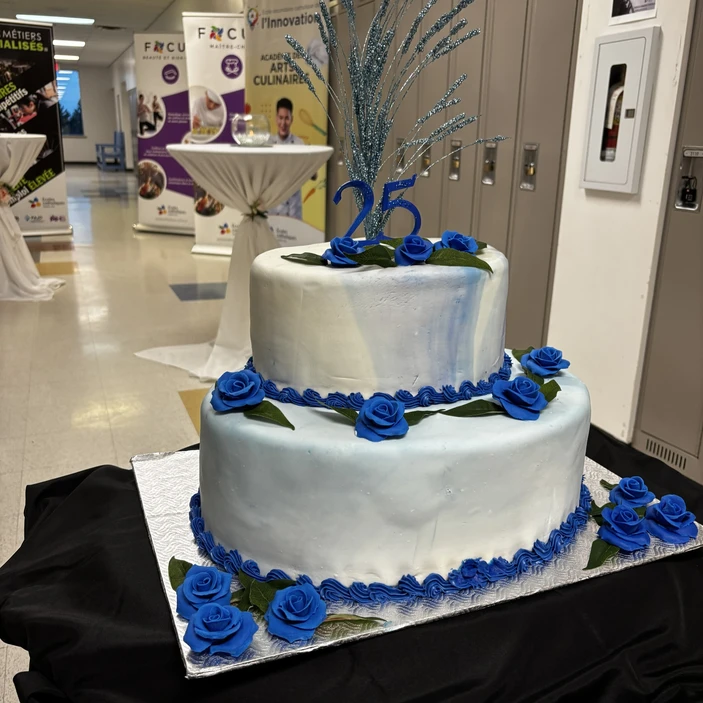Gâteau à deux étages décoré de roses bleues et d’un « 25 » pour un anniversaire.