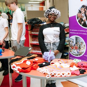 une élève avec le kiosque de son entreprise de tricot