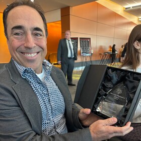 Pierre Thériault tient son trophée d’Éducateur de l’année des Olympiques spéciaux Ontario – Ottawa et sourit à l’objectif.