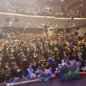Des finissantes et finissants lancent leurs mortiers en l’air devant une salle comble à la fin de la cérémonie de remise des diplômes.